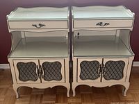 Pair of antique white French Provincial bedside tables with glass tops, drawer, open shelf, and wire mesh double-door cabinet.