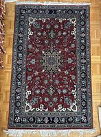 Full view of rectangular Persian style hand-knotted rug with central medallion and floral borders on wooden floor.