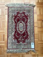 Top view of the rug showing the full pattern and fringe detail on parquet flooring.