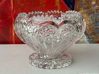 Front angled view of the vintage cut glass bowl showing heart-shaped patterns, starburst medallions, scalloped rim, and decorative base.