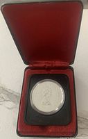 Silver Jubilee coin in red velvet-lined presentation case.