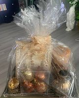 Full view of the clear wrapped gift tray showing all items including candle, vase, ornaments, jewelled cup, and picture frame.