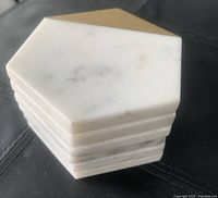 Stack of six white marble coasters in a hexagonal shape showing thickness and polished edges.