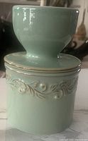 Side view of the butter crock showing the embossed scroll detailing and glossy sea spray green ceramic