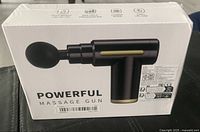 Front of sealed box showing the massage gun image and stating 'POWERFUL MASSAGE GUN'.