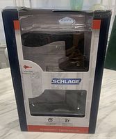 Photo of the new Schlage door handle in original packaging showing satin black finish and keyed entry lock set.