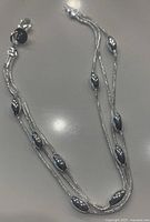 Top view of the multi-strand silver bracelet showing oval beads and lobster clasp on white background.