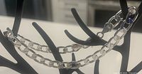 Close-up of shiny linked chain bracelet draped on black stand