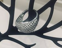 Silver ring displayed on a black decorative stand showing the texture and hollow dome shape.