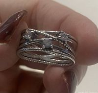 Close-up photo of the silver ring with three cubic zirconia stones showing twisted line design and beaded texture.