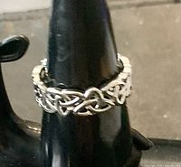 Front view of the sterling silver trinity knot ring on a black display stand, showing the detailed Celtic design.