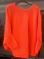Front view of bright orange knit sweater on hanger