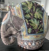 Front and side view of elephant-shaped tea cozy showing detailed textile pattern and curled trunk.