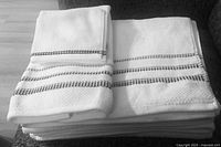 Image showing the stack of two bath towels with a hand towel and washcloth on top, all white with striped borders.