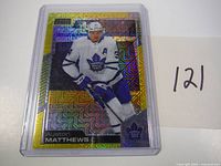 Front image of the 2020 OPC Platinum Auston Matthews hockey card numbered #026/249 showing player in white Toronto Maple Leafs uniform with gold holographic pattern.