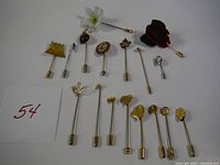 Full lot of 17 vintage stick pins arranged on white background, showing variety of designs including flower, cameo, crown, maple leaf, and hearts.