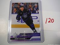 Front view of Bobby McMann Young Guns rookie card in protective case, showing player in black Toronto Maple Leafs uniform skating on ice.