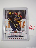 Front of 2014 Connor McDavid hockey card for Erie Otters showing player in black and yellow uniform, number 97, in action on ice.