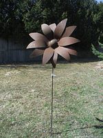 Outdoor photo showing the full 6-foot tall scrap metal flower on a metal stake in the lawn.