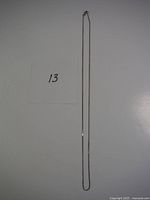 Full length image of a delicate chain measuring about 20 inches long alongside a label with number 13