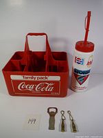 Photo of red Coca-Cola family pack bottle carrier and vintage soda cup with Pepsi and Arby's logos.