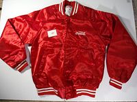 Full view of red satin Coca-Cola jacket laid flat with label showing size and embroidered logo.