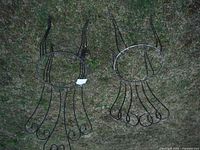 Two wrought iron garden chairs displayed on grass, top view showing seat frames without seating surfaces.