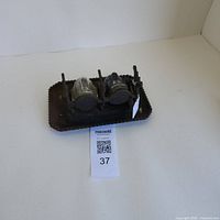 Top side view of antique ink well with metal tray base and two glass inkwells with lids.