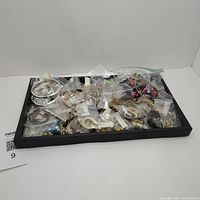 Full tray view of assorted bags of jewelry parts and pieces, showing variety and quantity.