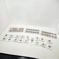 Overview of Canadian coins arranged in white flips and plastic holders on white background