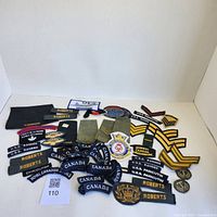 Overview of lot showing multiple Canadian military cloth badges, USS Ranger and USS Paricutin patches, metal insignia, and rank chevrons