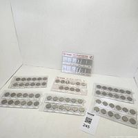 Overall view of the lot showing sets of Canadian quarters in plastic holders with date and theme labels.