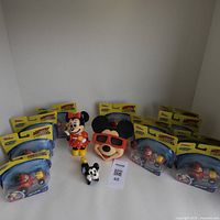 Overview of all items including 11 unopened Mickey Roadster Racers toy cars, ceramic Mickey Mouse figure, Minnie Mouse piggy bank, and View-Master