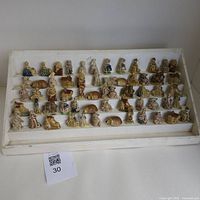 Wide view showing all 60 Wade figurines arranged on a white tiered stand, displaying a mix of characters, animals, and cottages.