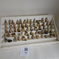 Front view of 60 various Wade ceramic figurines arranged on a white tiered display stand, showing a variety of small character and object designs.