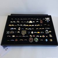 Full view of black display tray with approximately 85 assorted rings in multiple rows.