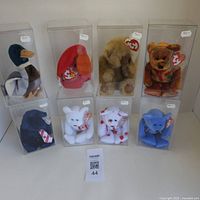 Front view of all 8 TY Beanie Babies in individual clear plastic display cases arranged in two rows.