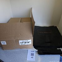 Photo showing half-full box labeled 'BLACK 17"X19" 500/CASE' with loose black plastic bags with 'Thank You' printed.