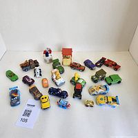 Toy cars spread out, showing different styles and colors including race cars, trucks, and character themed cars.