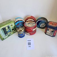 Overview shot of all 9 vintage collectible tins including multiple Planters tins and one green Watkins tin on white background.