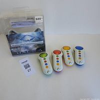 Photo showing the Xbox 360 Halo 4 controller in its original retail packaging and four Xbox Wireless Scene It controllers laid out beside it.