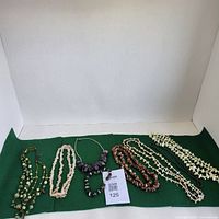 Photo showing six assorted mineral stone and crystal necklaces arranged on a green cloth background.