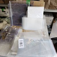 Collection of clear plastic sleeves, some resealable, in multiple sizes stacked on table with cardboard backing protectors visible