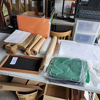 Full assortment of retail packing supplies laid out on a table including paper bags, craft paper rolls, bubble wrap, wooden display tray, and tissue paper.