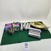 Full lot showing brass dish, incense boxes, incense rolls and incense burner arranged on green fabric.