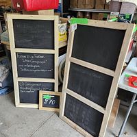 Front view of the two chalkboards showing the large wood-framed sign with three panels and the smaller gold-framed sign in front labeled with $70 price.