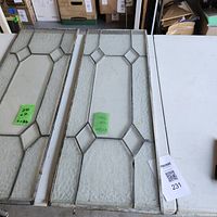 Two stained glass window panels placed side by side on a table, showing overall design and condition.