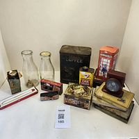 Full view of all collectibles including coffee tin, milk bottles, cigarette tin, pink phone booth bank, and stacked books with magnifier.