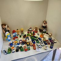 Full arrangement of vintage and antique toy lot including all figurines and die-cast cars displayed on white background.