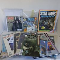 Photo showing a large lot of vintage Star Wars collectibles including magazines, books, comics and cassette tape, all stored in clear protective sleeves